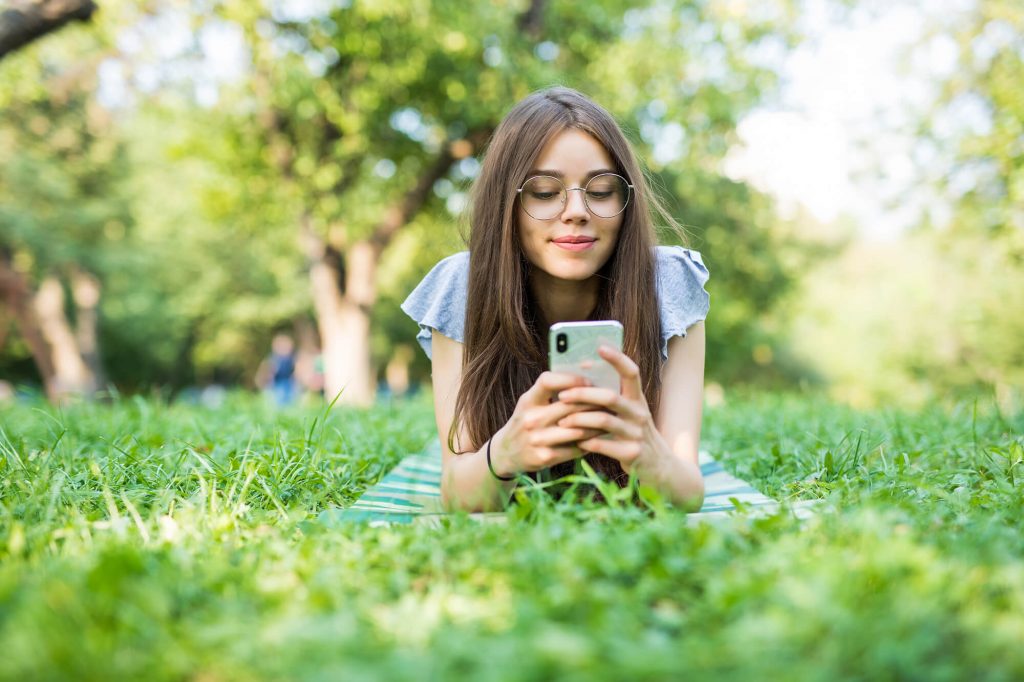 The Beautiful Woman Reading Phone Message On Grass